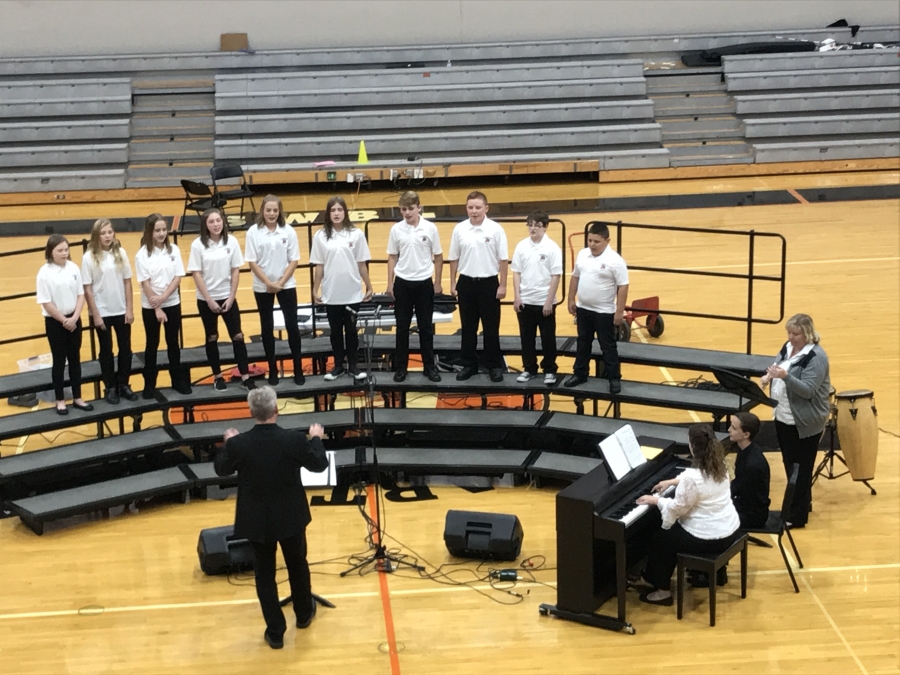 students in white shirts and a choir director